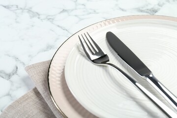Clean plates, cutlery and napkin on white marble table, closeup