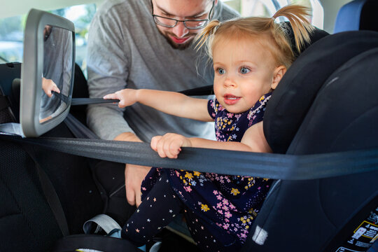 Dad buckling toddler into extended rear facing car seat