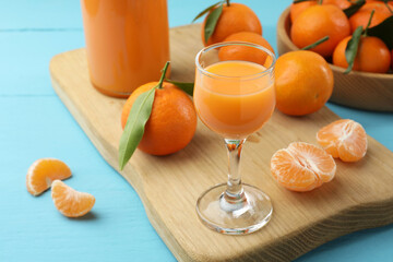 Delicious tangerine liqueur and fresh fruits on light blue wooden table