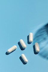 White capsules with vitamins or a dietary supplement on a blue background. Medicine, medicines