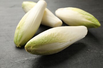 Fresh raw Belgian endives (chicory) on black table, closeup
