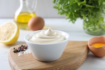 Tasty mayonnaise sauce in bowl, spices and ingredients on white table, closeup