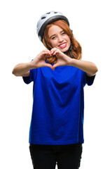 Young beautiful woman wearing cyclist helmet over isolated background smiling in love showing heart symbol and shape with hands. Romantic concept.