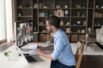 Serious millennial businessman sit at desk with PC in modern home-office take part in videoconference talk with colleagues, engaged in briefing with partners using application. Virtual meeting event