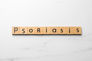 Word Psoriasis made of wooden squares with letters on white marble table, top view