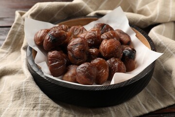 Roasted edible sweet chestnuts in bowl on table, closeup
