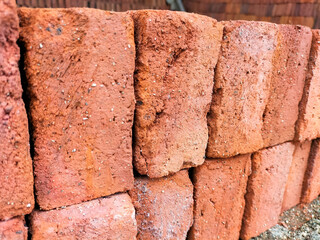 Selective focus. Red bricks from clay. Many clay is molded into bricks, after that it is laid out and dried in the yard in the sun before being burned to make it hard and dry. Pile of making batu bata