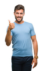 Young handsome man over isolated background doing happy thumbs up gesture with hand. Approving expression looking at the camera with showing success.