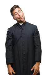 Fototapeta premium Young catholic christian priest man over isolated background making fish face with lips, crazy and comical gesture. Funny expression.