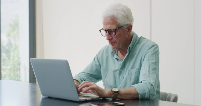 Home, typing and senior man with laptop, internet and glasses with website information, email and network. Apartment, pensioner and mature guy with a computer, check retirement fund and eyewear