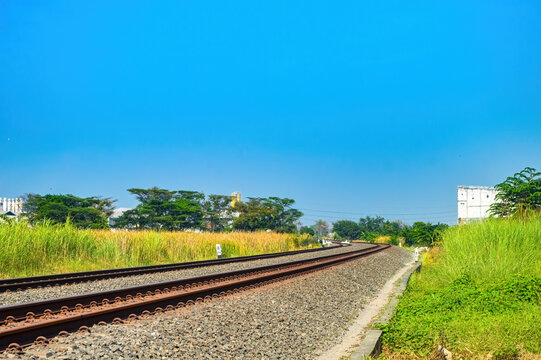 double track railway track that curves across the north of the island of Java with a bright blue sky