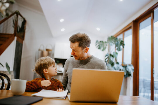 Father and young son doing homework together at table