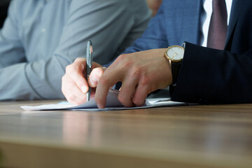 Man is concentrating on signing a document during a business meeting or negotiation. Signing an...
