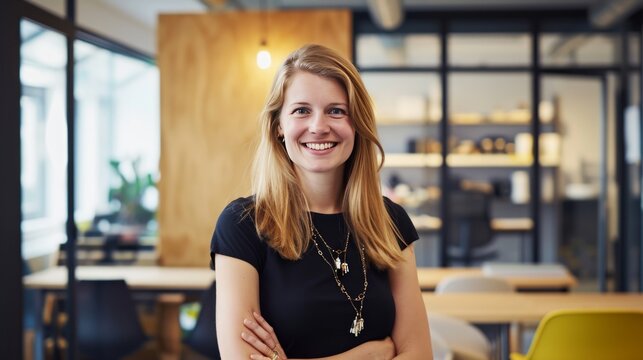 Angestellte Frau im B&uuml;ro. Mitarbeiterin im Office l&auml;chelt in die Kamera. Modernes Startup Business. Junge Frau mit langen Haaren und nat&uuml;rlichem Look.