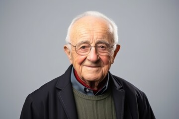 Portrait of a senior man with glasses on a gray background.