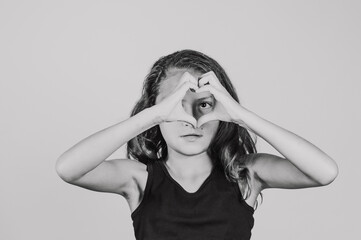 A tween Hispanic girl with her hands forming a heart shape.