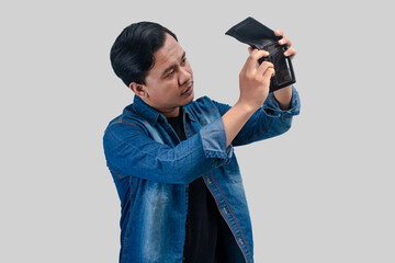 Young Asian man showing sad face expression while holding his empty wallet