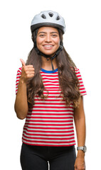 Young arab cyclist woman wearing safety helmet over isolated background doing happy thumbs up gesture with hand. Approving expression looking at the camera with showing success.