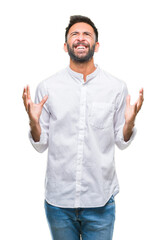 Adult hispanic man over isolated background crazy and mad shouting and yelling with aggressive expression and arms raised. Frustration concept.