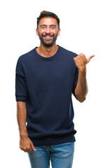 Adult hispanic man over isolated background smiling with happy face looking and pointing to the side with thumb up.