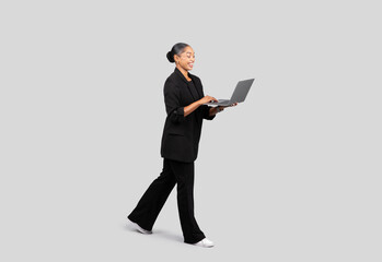 A dynamic young businesswoman in motion, dressed in a black suit