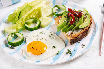 Romantic breakfast for Valentine's Day. Fried egg and toast with avocado and cream cheese.