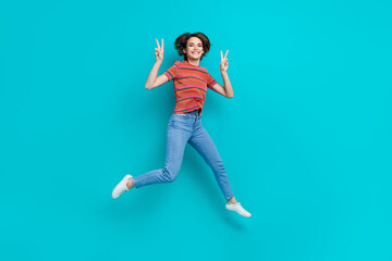 Fototapeta na wymiar Photo of adorable cheerful girl wearing stylish outfit walking running showing v-sign isolated on cyan color background