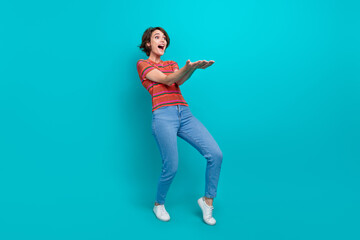 Fototapeta na wymiar Full length photo of adorable cheerful girl wear trendy clothes hold novelty product look empty space isolated on cyan color background
