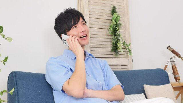 自宅でスマートフォンで電話する男性
