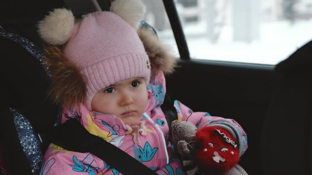A small child rides in a car in a child seat. Winter in the background