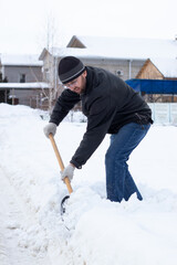 A man with a snow shovel cleaning snow from a sidewalk on the street on cold winter day, doing snow removal