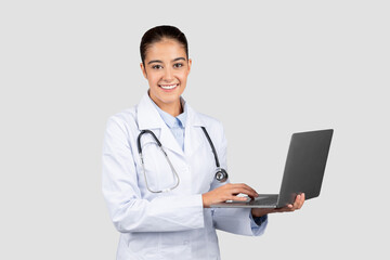 Happy millennial caucasian doctor typing on computer, chatting with patient remotely