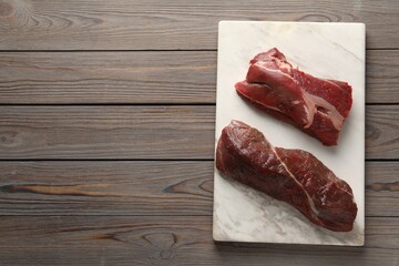 Pieces of raw beef meat on wooden table, top view. Space for text