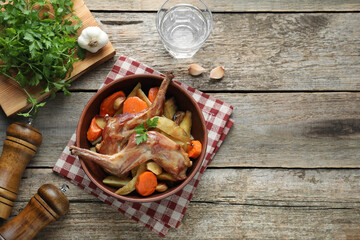 Tasty cooked rabbit with vegetables served on wooden table, flat lay. Space for text