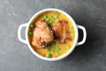 Tasty cooked rabbit meat with sauce and peas on grey table, top view