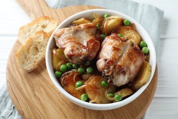 Tasty cooked rabbit with vegetables in bowl on white wooden table, closeup