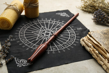 Magic wand, divination cloth, old book and wax candles on light table, closeup