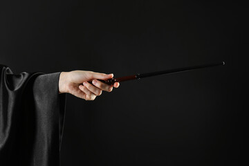 Wizard holding magic wand on black background, closeup