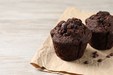 Delicious chocolate muffins on light wooden table, closeup. Space for text