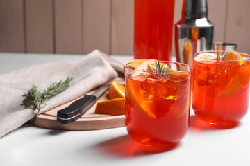 Aperol spritz cocktail, rosemary and orange slices on white wooden table