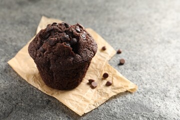 Delicious chocolate muffin on grey textured table, closeup. Space for text