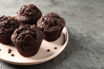 Delicious chocolate muffins on grey textured table, space for text