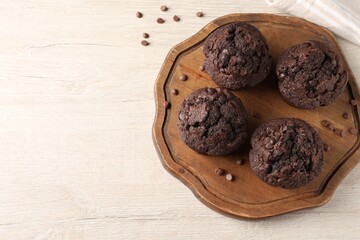 Delicious chocolate muffins on white wooden table, top view. Space for text