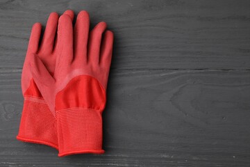 Pair of red gardening gloves on grey wooden table, top view. Space for text