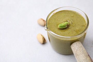 Tasty pistachio cream and nuts on white table, closeup. Space for text