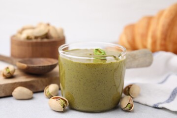 Tasty pistachio cream and nuts on light table, closeup