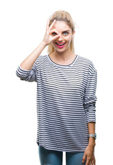 Young beautiful blonde woman wearing stripes sweater over isolated background doing ok gesture with hand smiling, eye looking through fingers with happy face.