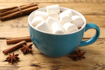 Tasty hot chocolate with marshmallows and spices on wooden table, closeup