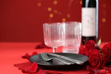 Place setting with roses for romantic dinner on red table, closeup. Space for text