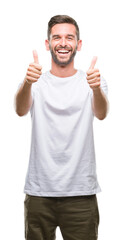 Young handsome man over isolated background success sign doing positive gesture with hand, thumbs up smiling and happy. Looking at the camera with cheerful expression, winner gesture.